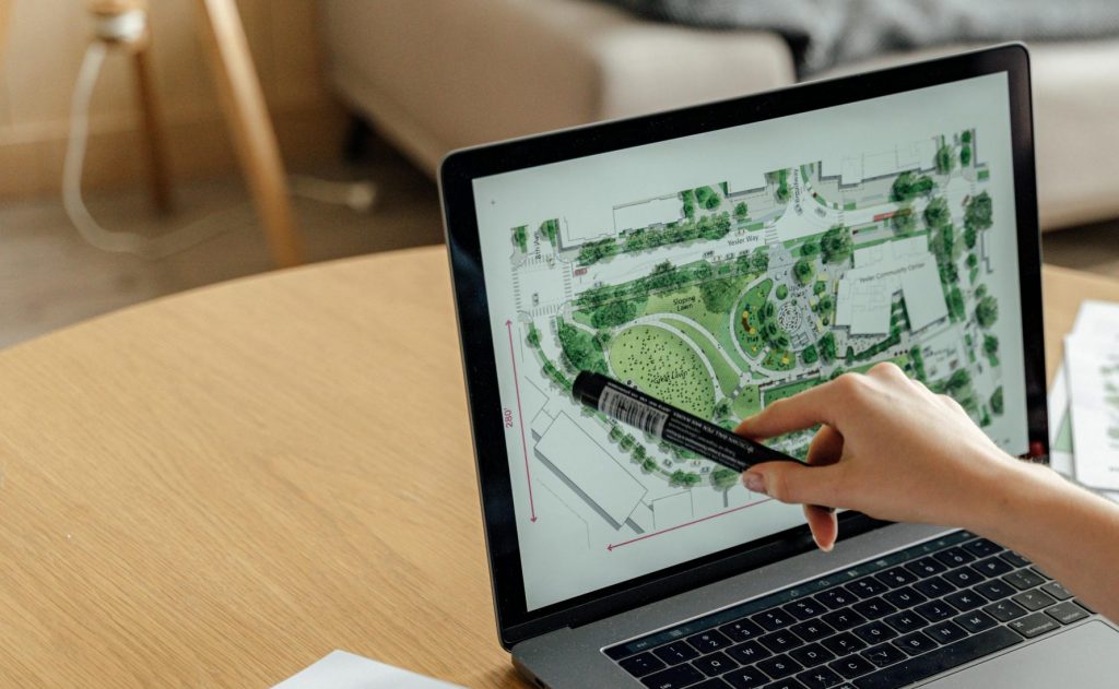 Architect reviewing landscape design on laptop, enhancing architectural projects from home office.